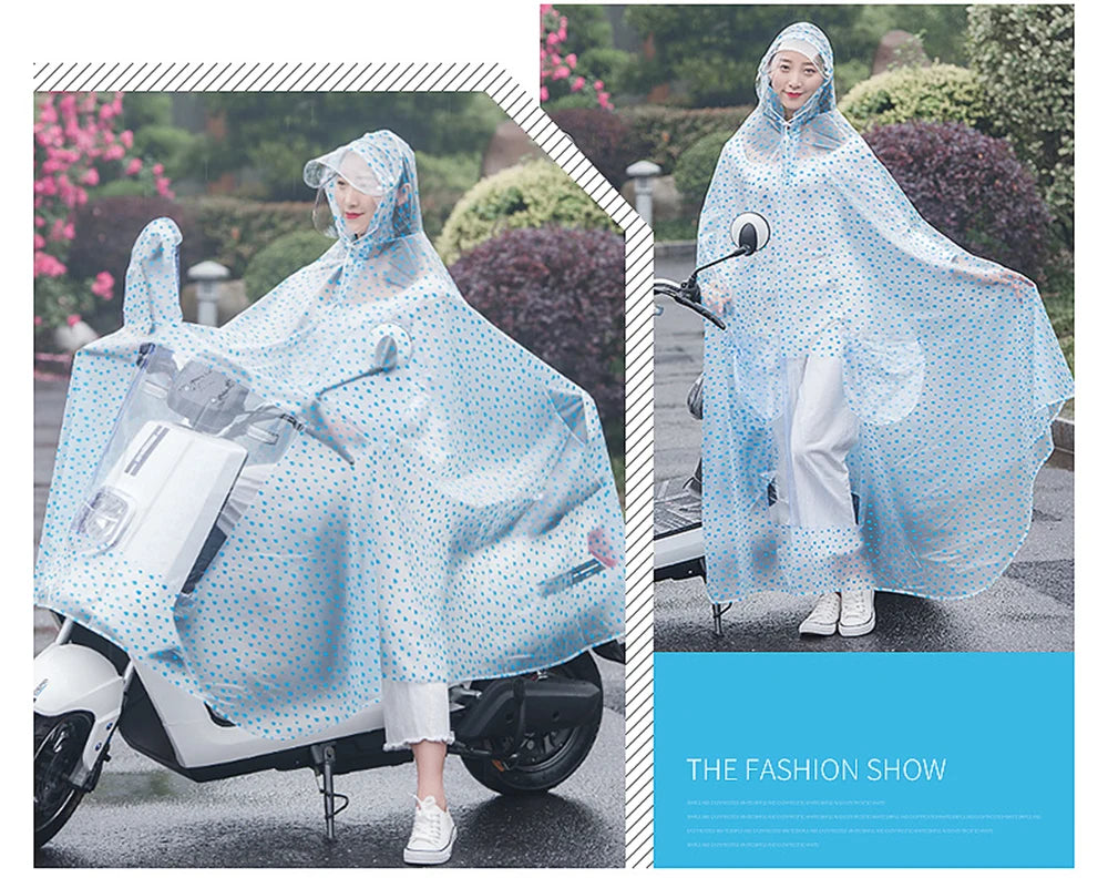 A woman wearing a transparent blue dotted waterproof motorcycle rain poncho with a hood standing on a motorcycle.