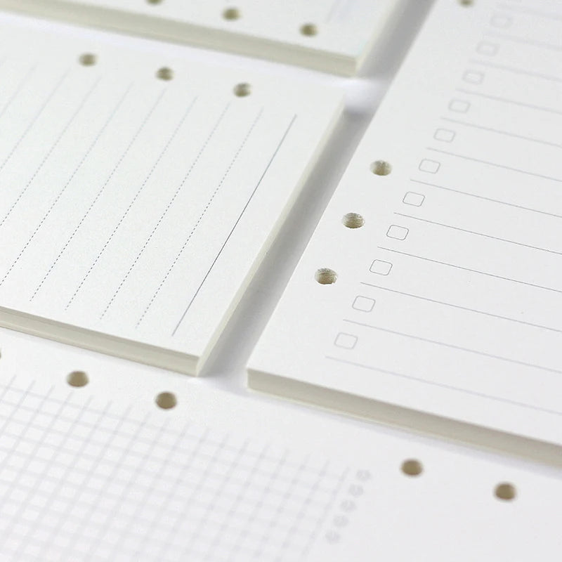 Close-up view of loose leaf notebook refill paper sheets with ruled lines and dotted guides.