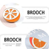 A round enamel brooch pin shaped like a slice of orange with white segments.