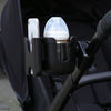 A black phone holder attaches to a stroller handlebar, holding an iPhone and a clear cup.