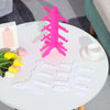 A bright pink acrylic stand shaped like a tree is displayed on a white table next to white eyeglass holders.