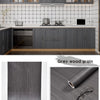Roll of self-adhesive wood grain wallpaper film showing a textured grey finish.