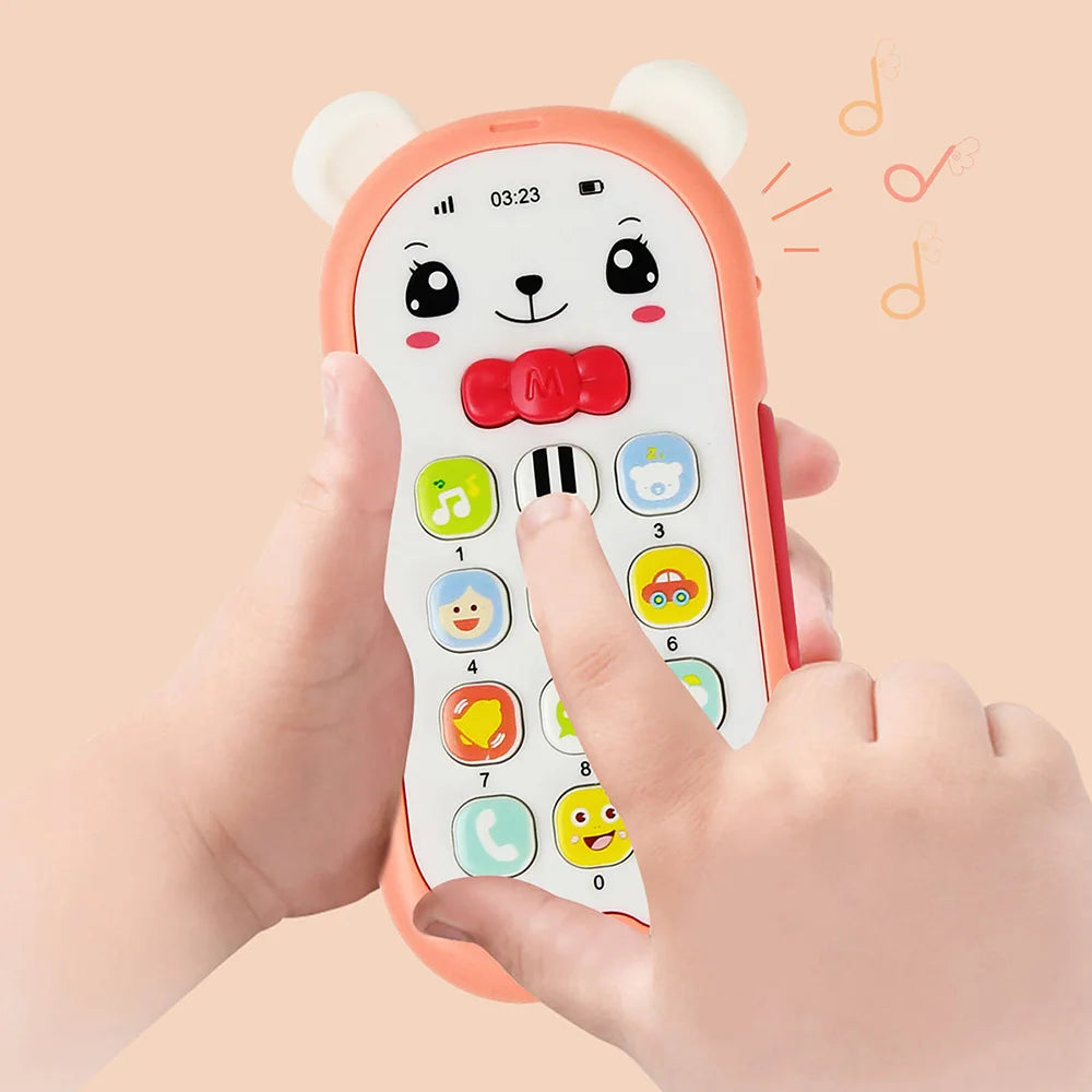 A hand is holding an orange musical teether phone toy with a bear face and colorful buttons.