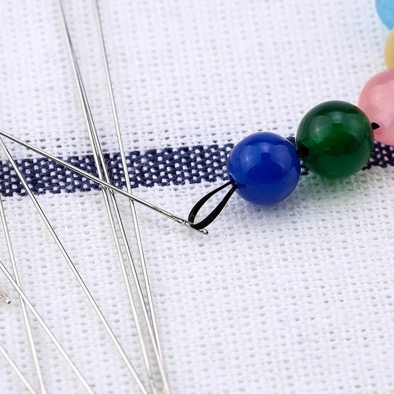 Stainless steel beading needles with colorful beads on a white background