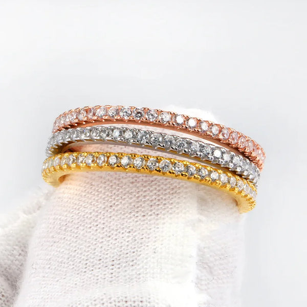 Une pile de trois bagues de mariage or et fines, ornées de diamants de différentes couleurs.