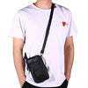 A person wearing a white t-shirt holds a black leather multi-pocket waist bag.