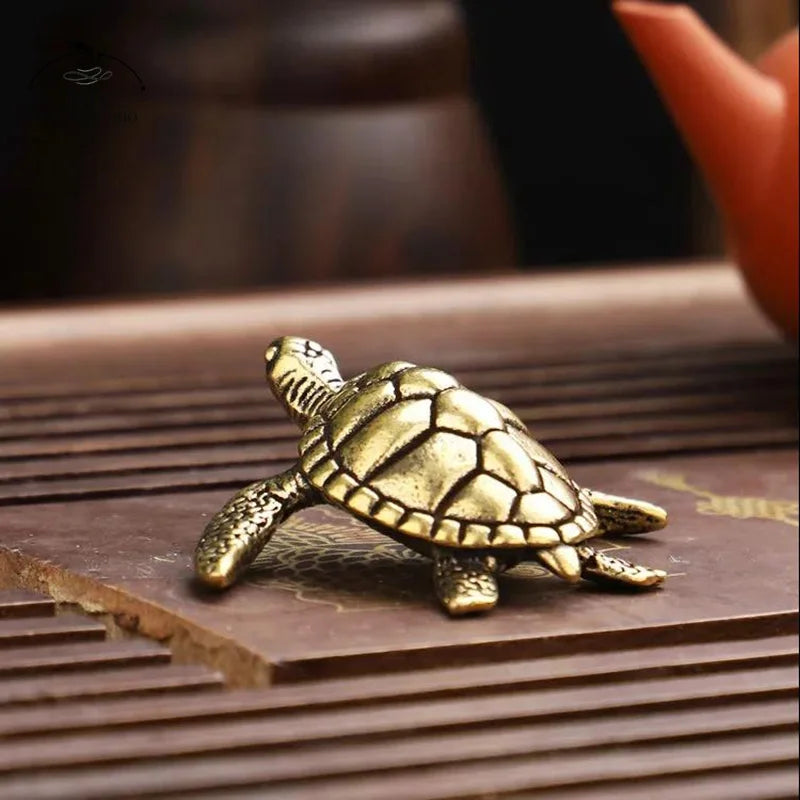A golden copper turtle figurine resting on a dark wooden surface.