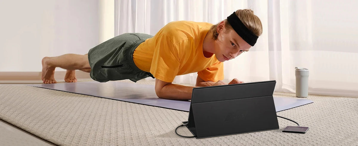 Eine Person nutzt einen tragbaren Full-HD- externen Monitor beim Yoga auf einer Matte.