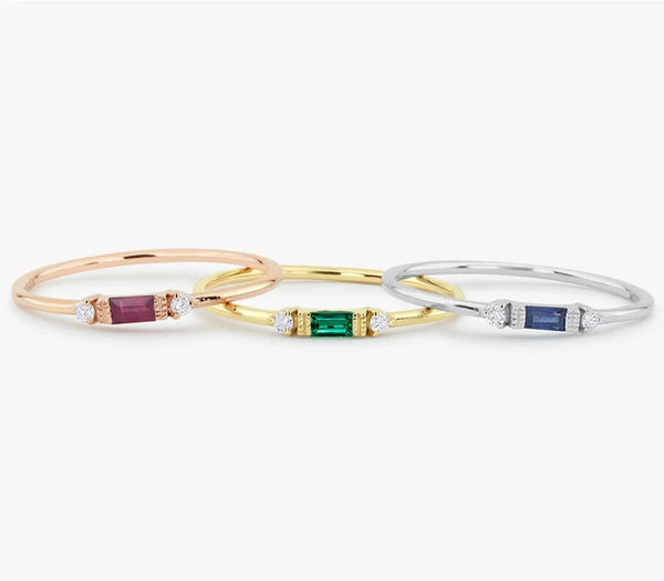 Un jeu de trois bagues or et argent avec des pierres précieuses de couleurs variées comme le rubis, l'émeraude et le saphir.