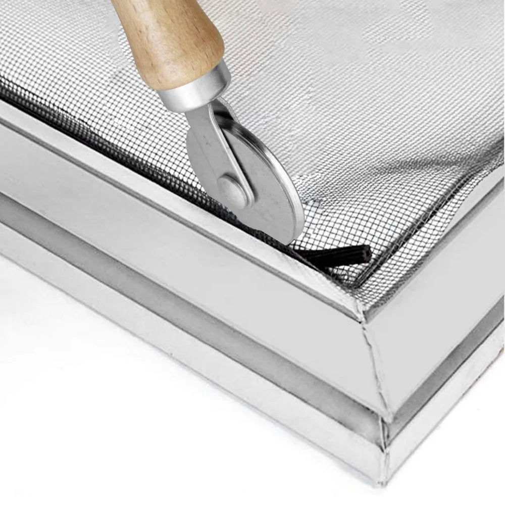 A close-up view of a DIY insect screen mesh kit with a silver rolling tool and wooden handle resting on a metal frame.