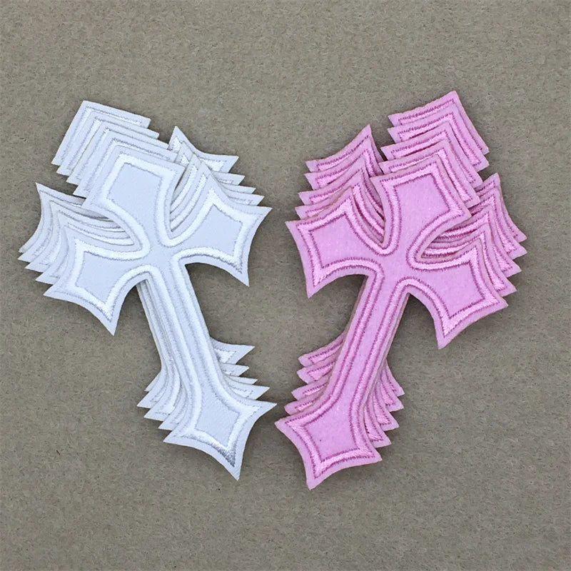 A set of two embroidered cross iron-on patches, one white and one pink, displayed on a neutral background.