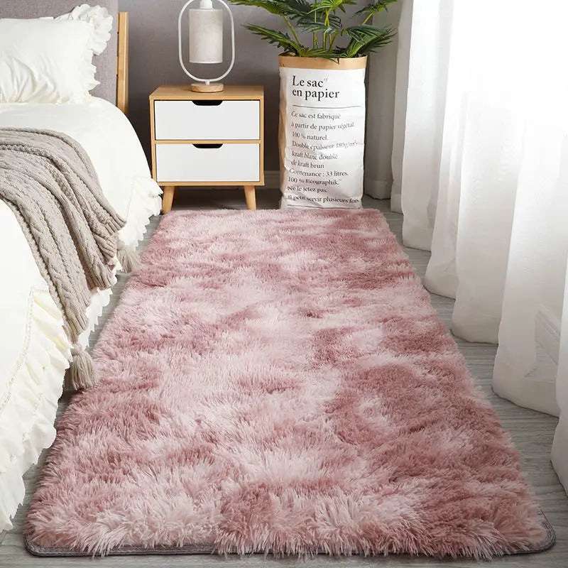 A fluffy pink Nordic fur rug placed in a bright room next to a wooden nightstand and a potted plant.