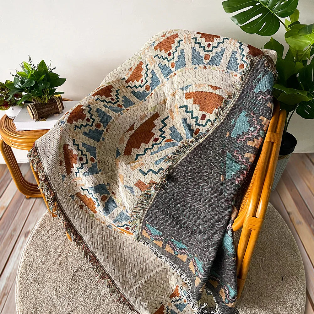 A woven throw blanket featuring a bohemian jacquard pattern in earthy tones of brown, teal, and beige.