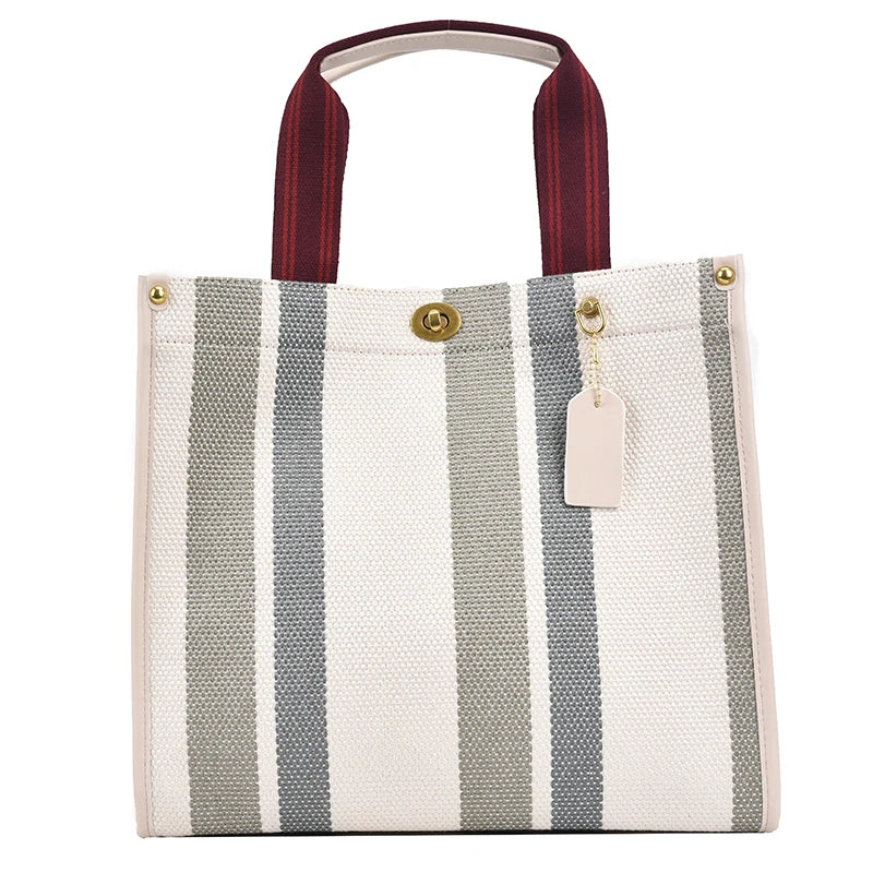 A white canvas tote bag with gray stripes and a maroon strap.