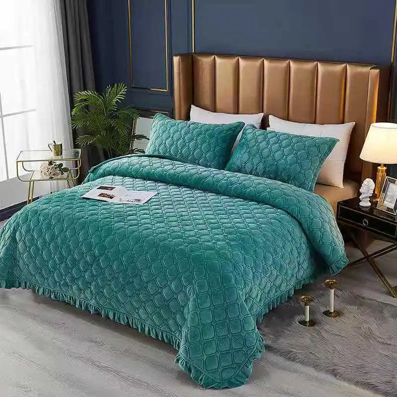 A teal quilted velvet bedspread with a fringed edge is displayed on a bed in a modern bedroom setting.
