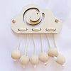 A wooden cloud shaped busy board with hanging parts for fine motor skill development.