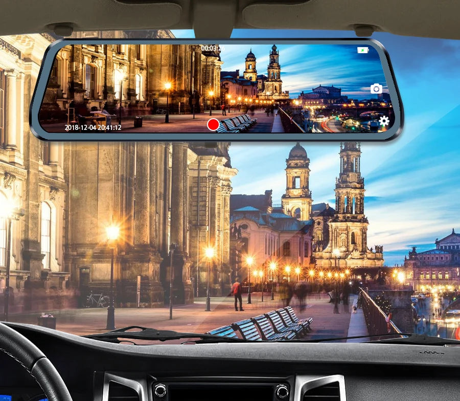 Interior view of a car showing a wide-angle dash cam recording a nighttime cityscape with illuminated buildings.