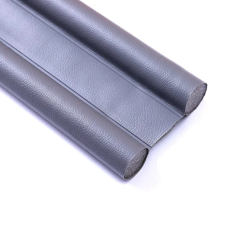 A close-up view of a gray flexible door bottom sealing strip or weatherproofing draft guard.