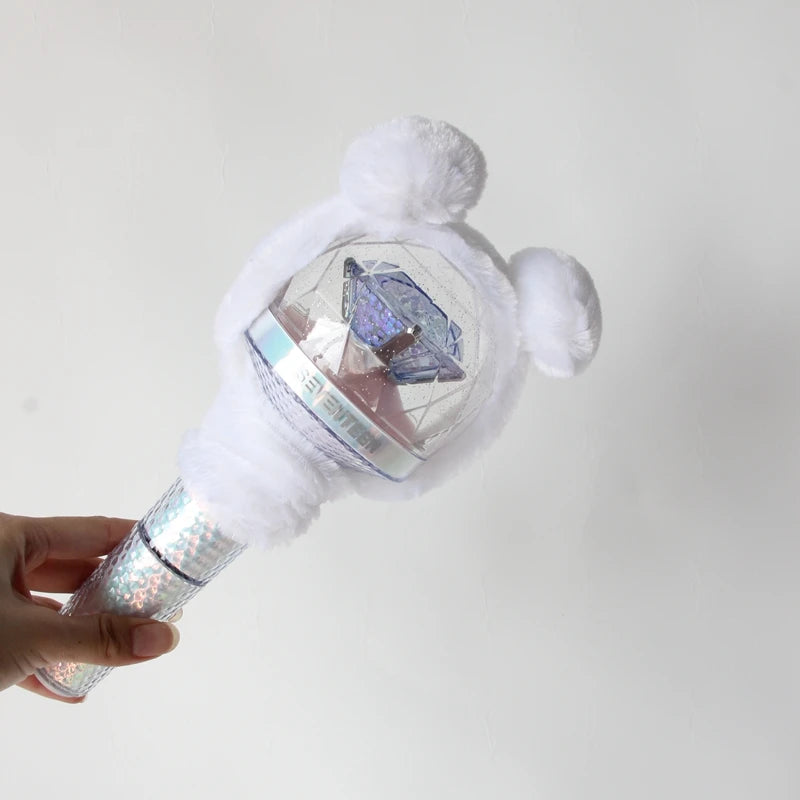 A hand holds a plush cover for a SEVENTEEN official light stick, featuring white fluffy material and a clear dome.