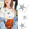 A woman wearing a white top and denim jacket, holding glitter rhinestone star patches.