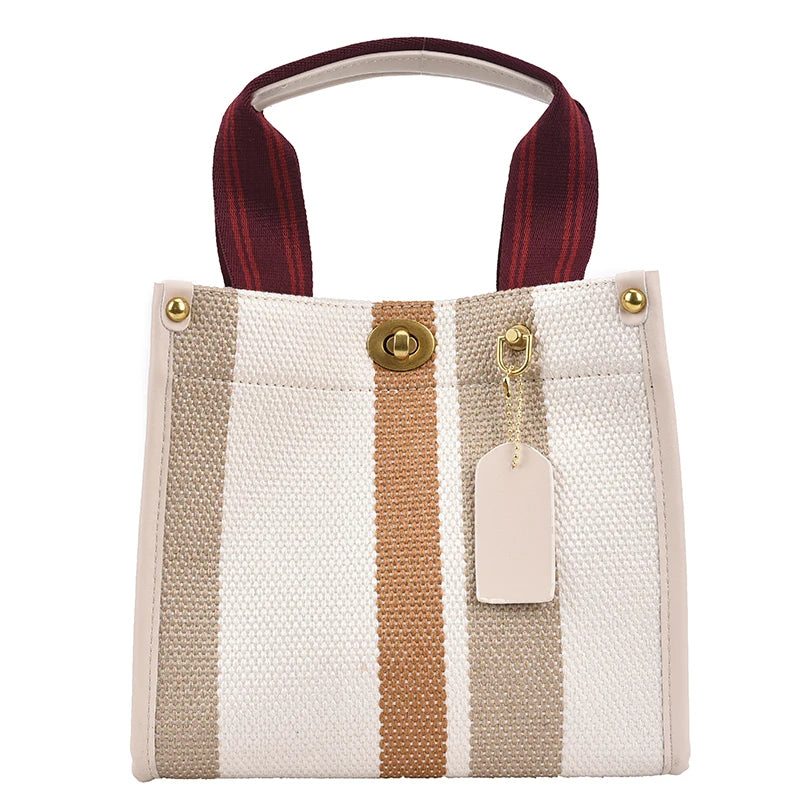 A beige canvas crossbody tote bag with vertical stripes and a brown leather strap.
