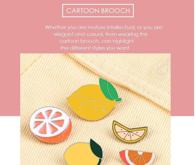 A collection of enamel fruit brooches featuring citrus slices like lemon, orange, and lime on a beige fabric background.