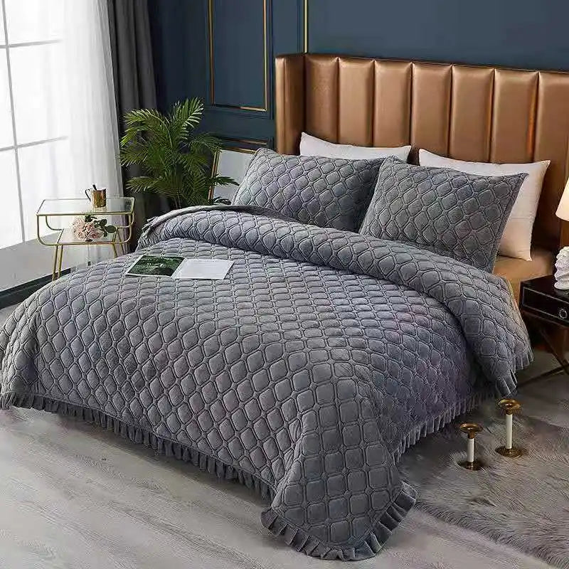 A gray quilted bedspread with a textured pattern is displayed on a bed in a modern bedroom setting.