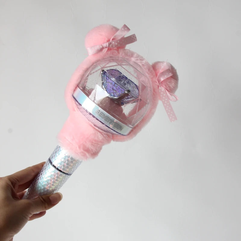 A hand holds a plush pink cover with a clear dome and purple crystal inside, designed for a SEVENTEEN official light stick.