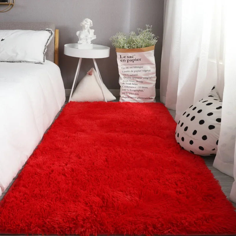A bright red extra large Nordic fur rug placed on a bed with white linens and a potted plant.