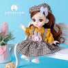 A brown-haired fashion doll wearing a yellow outfit and checkered skirt with a pink bow, sitting on a white wooden chair.