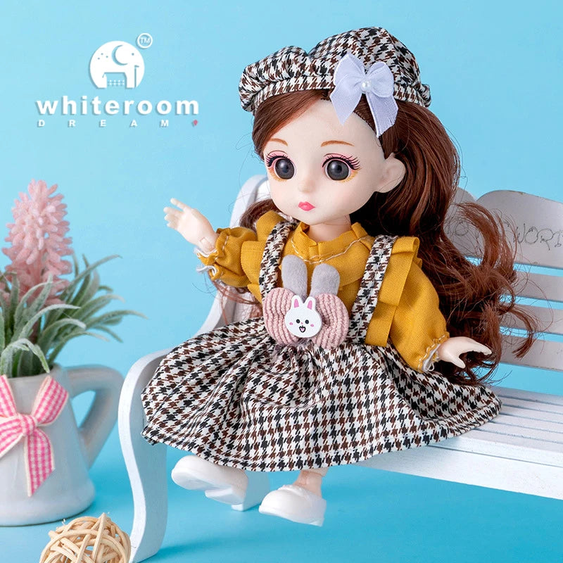 A brown-haired fashion doll wearing a yellow outfit and checkered skirt with a pink bow, sitting on a white wooden chair.
