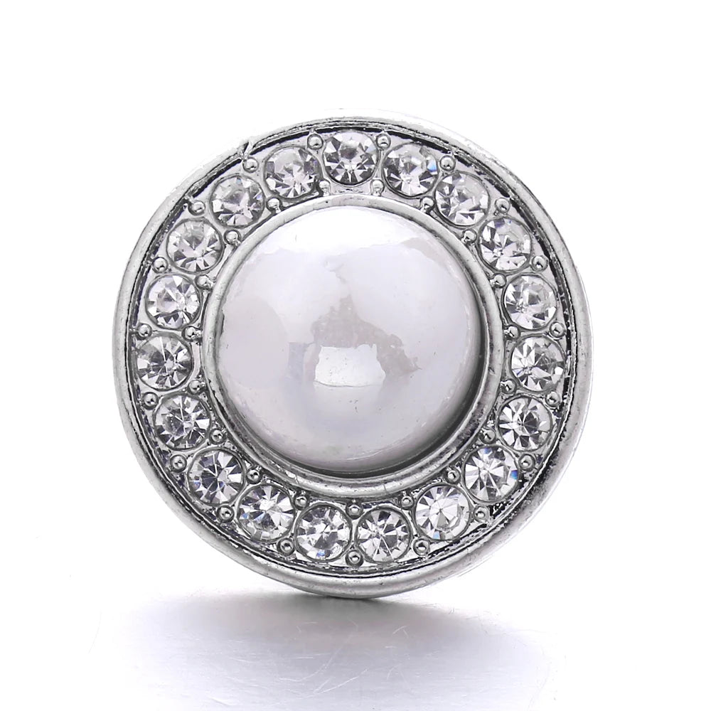 Silver snap button with a round, clear gemstone center surrounded by a halo of small clear stones