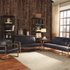 A living room interior featuring dark wood grain wallpaper, leather seating, and natural light.