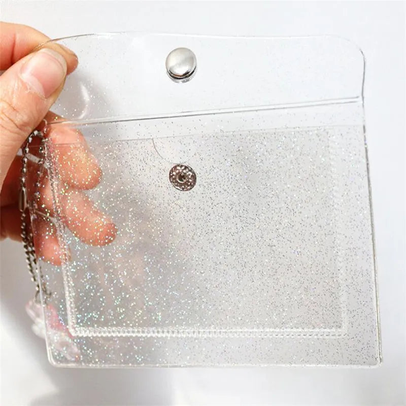 A clear glitter PVC card holder with silver snap closures is held by a hand.