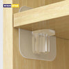 A close-up view of a clear plastic adhesive shelf support peg mounted on a wooden cabinet panel.