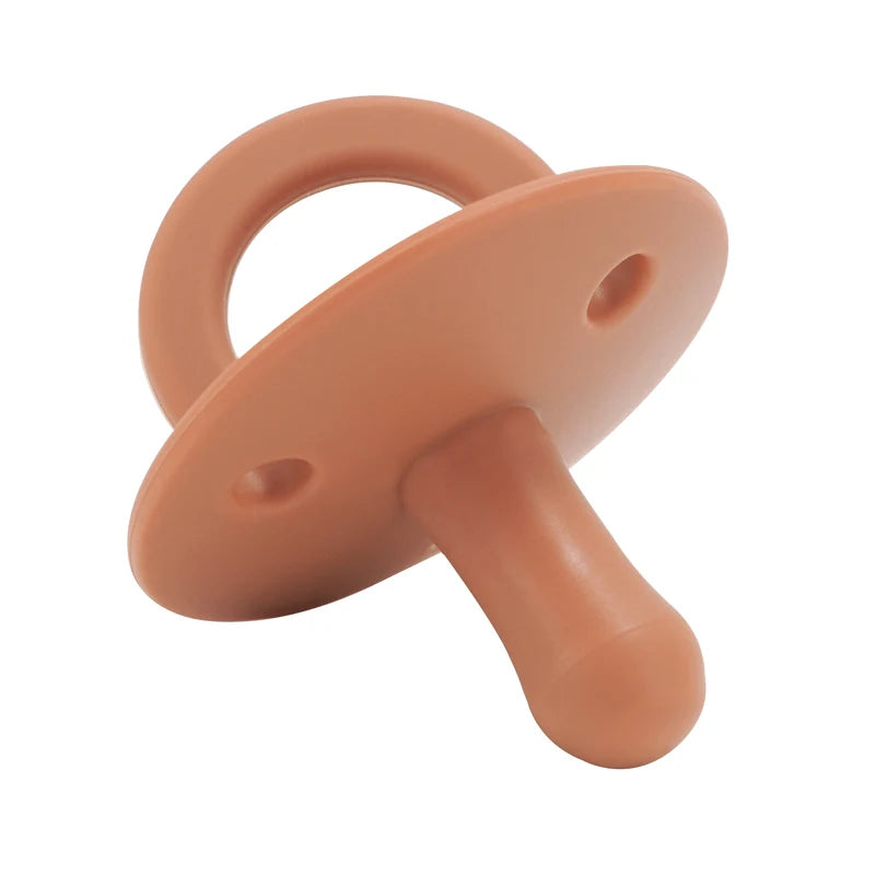 A soft peach silicone baby pacifier soother with a rounded handle and a tapered tip.