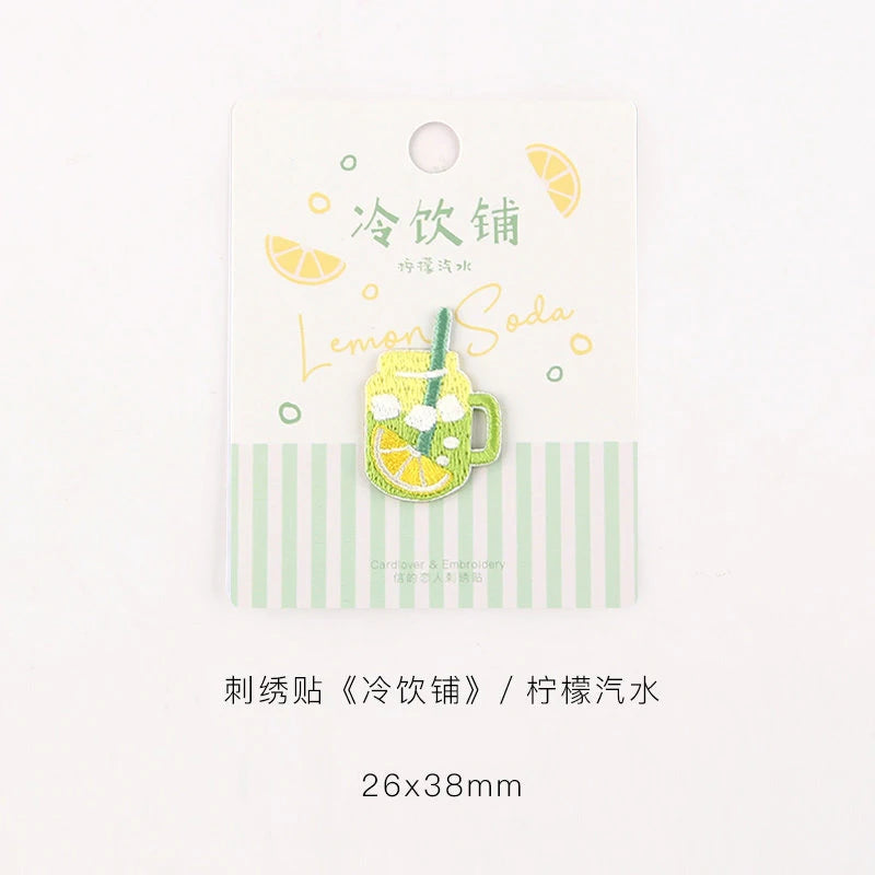 Embroidered iron-on patch featuring a yellow lemonade glass with lime slices and green leaves on a white background.