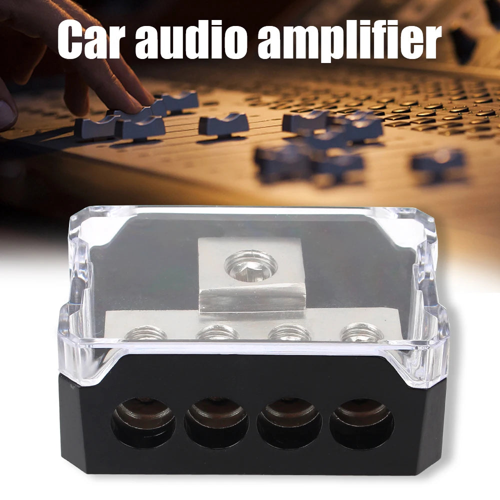 A black plastic car audio amplifier power distribution block with four terminals and a fuse.