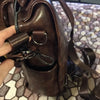A close-up of a brown PU leather fashion backpack showing the zipper and hardware details.