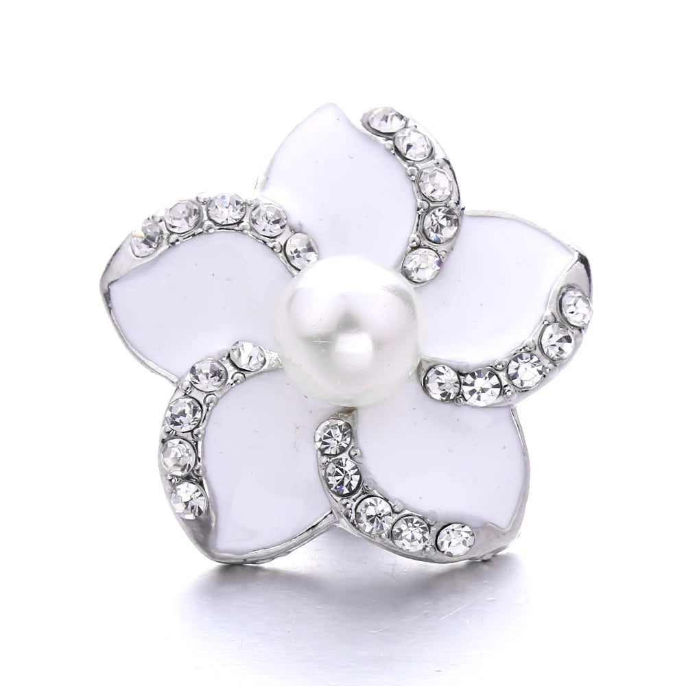 A white flower-shaped button with a pearl center and surrounding clear rhinestones for jewelry making