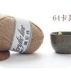 A ball of beige acrylic yarn with a gray label next to a small, speckled ceramic bowl.