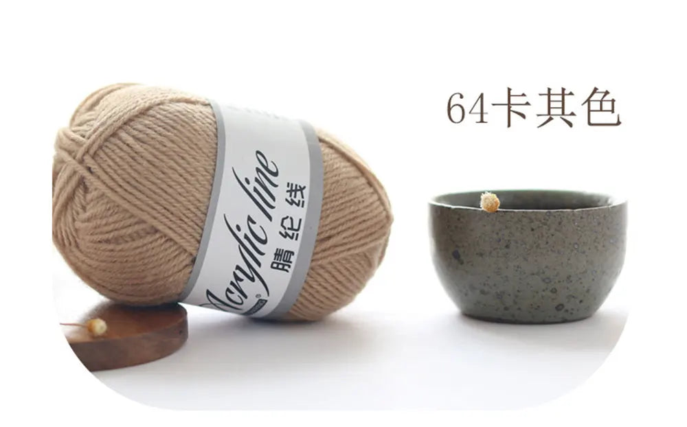 A ball of beige acrylic yarn with a gray label next to a small, speckled ceramic bowl.