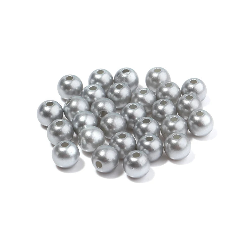 A pile of round silver-colored ABS imitation pearl beads for jewelry making.