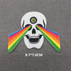 White skull design with a rainbow arching across the eye sockets, embroidered iron-on patch.