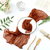 A brown cotton gauze table runner draped elegantly on a white plate with floral and greenery accents.