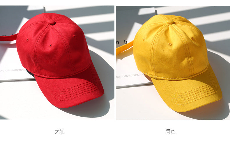 A pair of classic cotton dad hats in red and yellow shown side by side on a white surface.