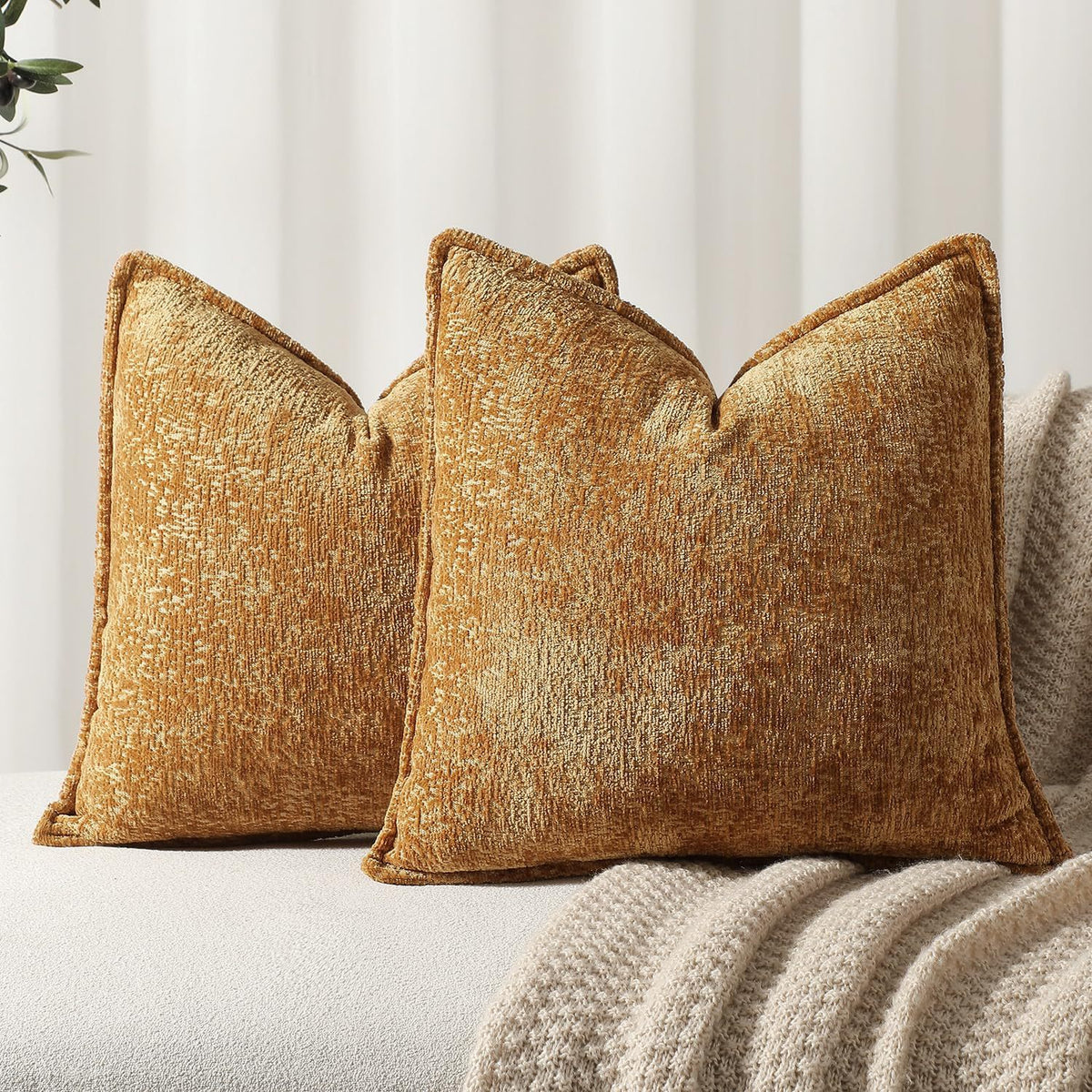 Two textured mustard yellow chenille throw pillows resting on a light gray fabric.