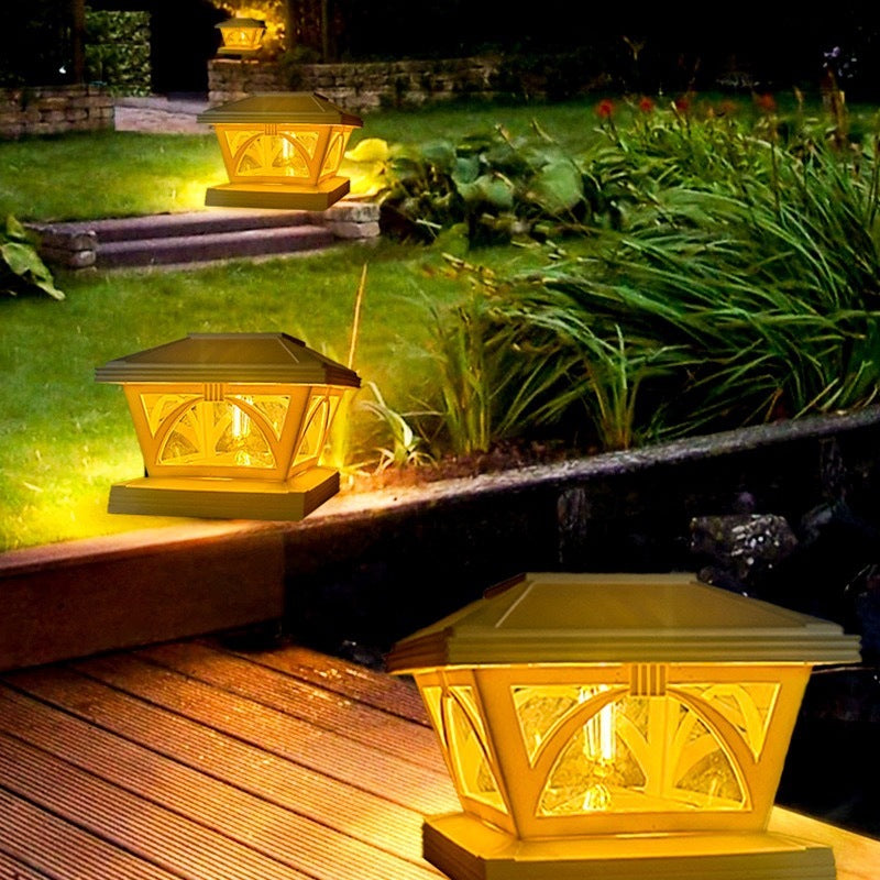 A yellow solar post cap light illuminates a garden area at night.