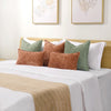 A collection of soft chenille throw pillow covers in earthy tones including olive green, terracotta, and cream on a white bed