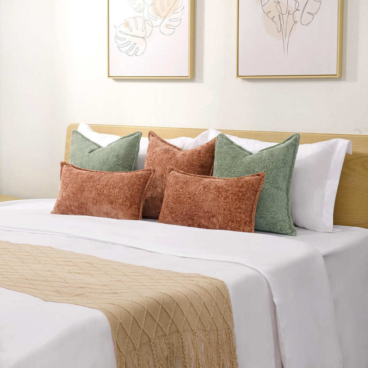 A collection of soft chenille throw pillow covers in earthy tones including olive green, terracotta, and cream on a white bed